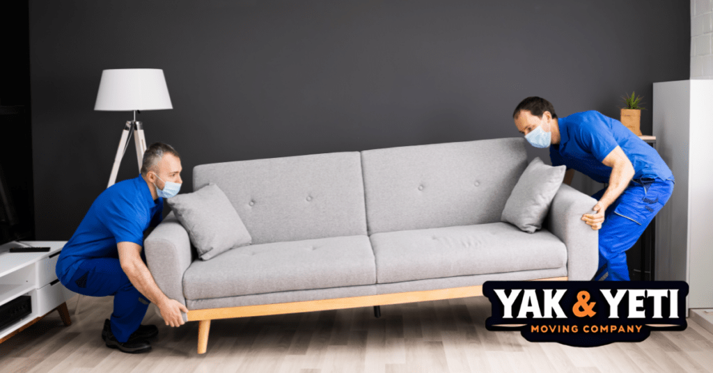 two men wearing face masks and sitting on a couch