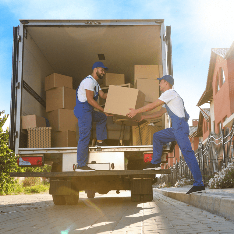 men in blue overalls loading boxes into a truck