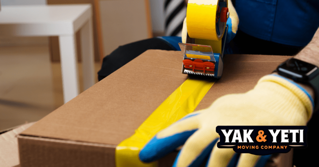 a person with gloves and tape dispenser on a box